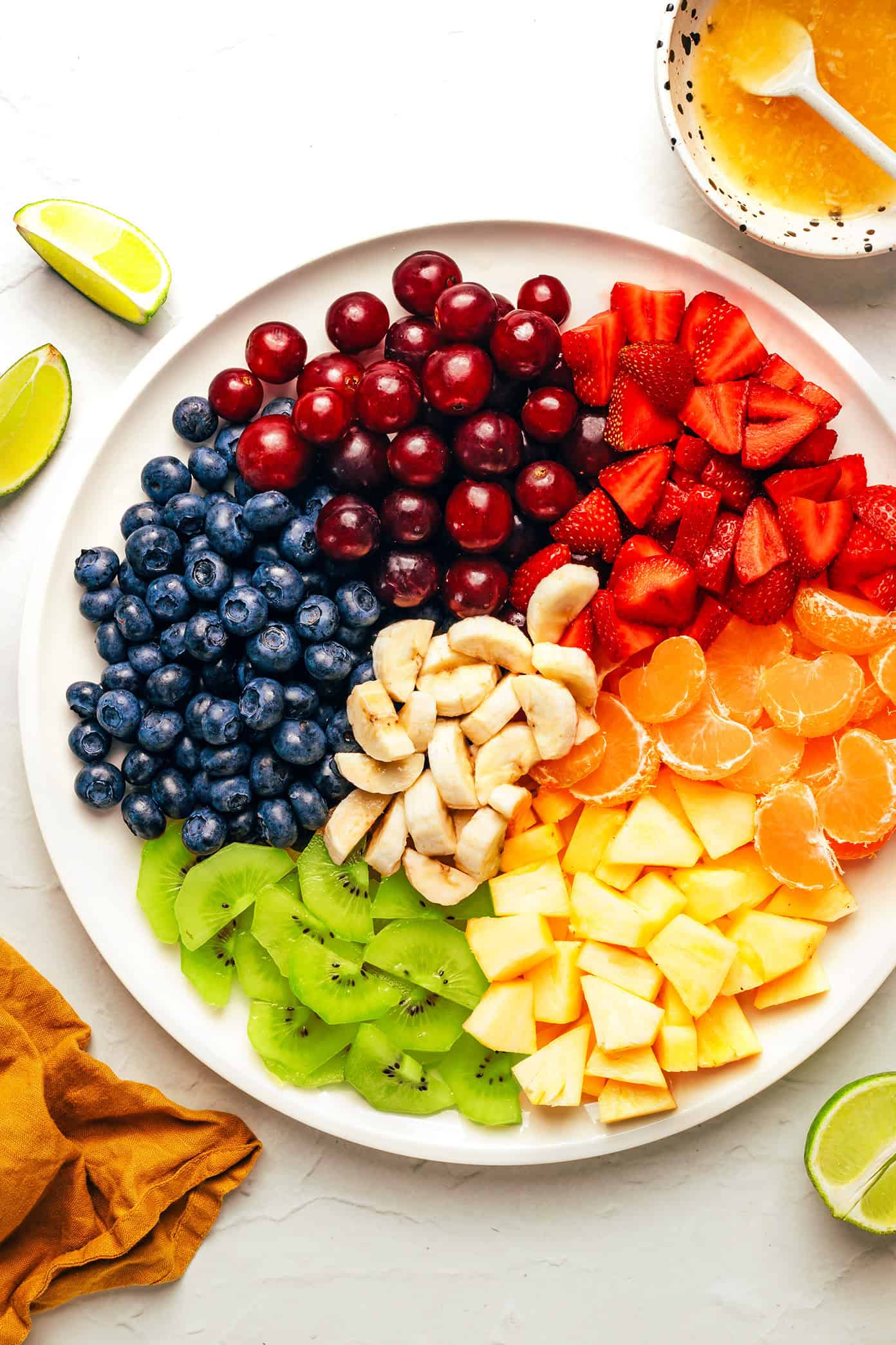 This easy fruit salad recipe features a rainbow mix of fresh fruit tossed in a zippy ginger-lime dressing. It's the perfect colorful side dish for picnics, grill nights or summer dinners! | gimmesomeoven.com fruit salad ingredients