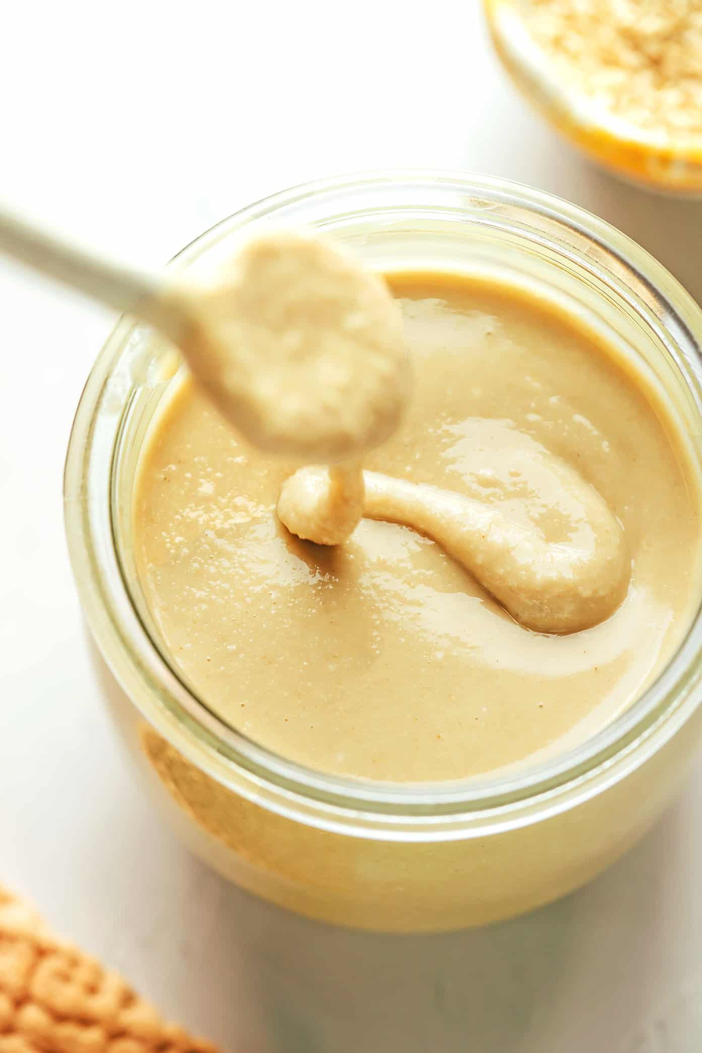 This homemade tahini recipe is easy to make with 3 ingredients and tastes so deliciously nutty and creamy. Use this Middle Eastern condiment to make dips like hummus or baba ganoush, or add it to everything from salad dressings to smoothies, baked goods and more. Naturally gluten-free, vegetarian and vegan. | gimmesomeoven.com Homemade tahini drizzled into a jar