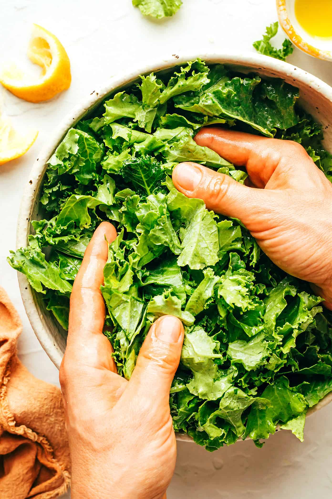 This easy kale salad recipe only takes 5 minutes to make with kale, Parmesan, sliced almonds, lemon, olive oil, and tastes great with just about everything! Feel free to add extra veggies or a protein (such as chicken, shrimp, salmon, etc) if you'd like. | gimmesomeoven.com Demonstrating how to massage kale