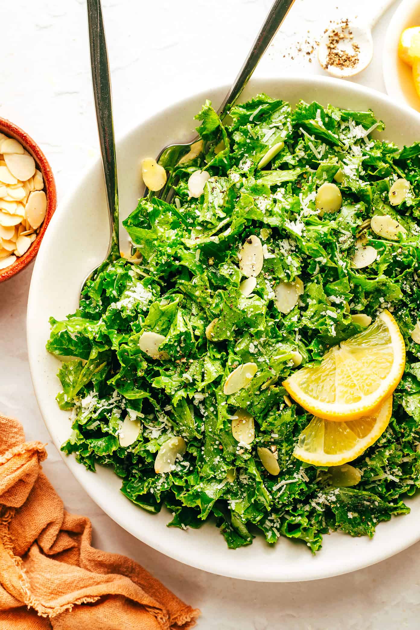 This easy kale salad recipe only takes 5 minutes to make with kale, Parmesan, sliced almonds, lemon, olive oil, and tastes great with just about everything! Feel free to add extra veggies or a protein (such as chicken, shrimp, salmon, etc) if you'd like. | gimmesomeoven.com Kale Salad with Lemon, Parmesan and Almonds in Serving Bowl