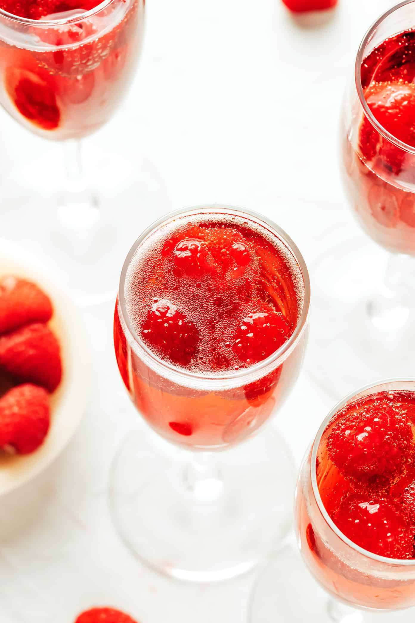 This classic kir royale cocktail recipe is easy to make with dry sparkling wine (such as Champagne, cava or prosecco), crรจme de cassis (blackcurrant liqueur) and your choice of berries for garnish. It's a vibrant, bubbly, refreshing drink that's perfect for summertime! | gimmesomeoven.com Closeup of kir royale drinks