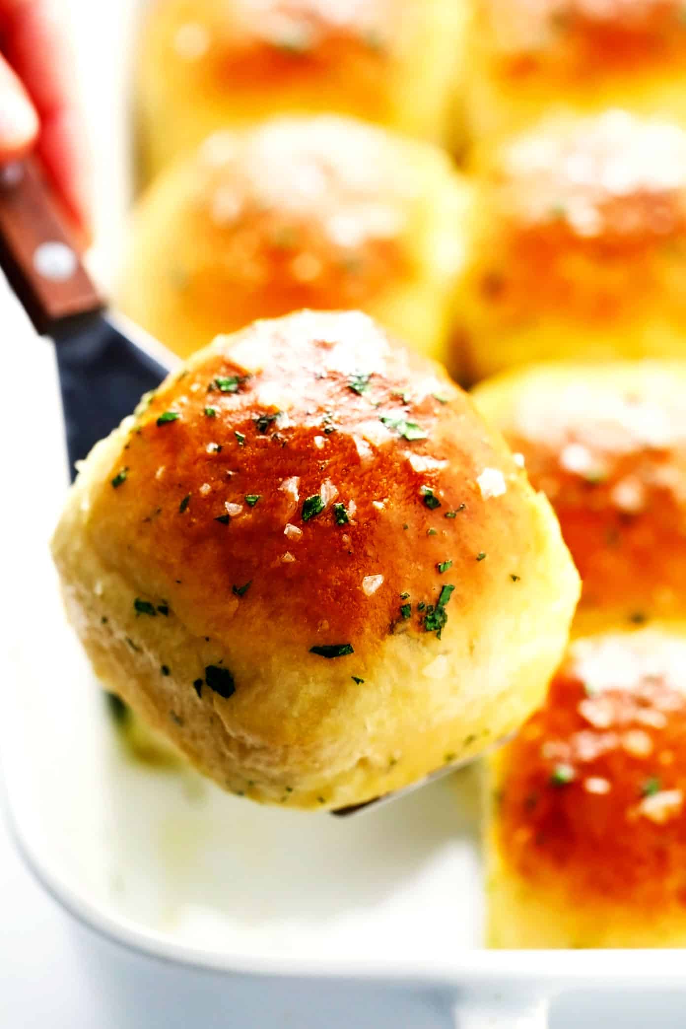 This rosemary garlic dinner rolls recipe is perfectly soft and fluffy, easy to make with or without a stand mixer, brushed with garlic herb butter and sprinkled with flaky sea salt, and ready to go in about one hour! Always a fantastic side dish for holidays like Thanksgiving, or the perfect easy bread recipe for weeknight dinners too. Vegan option included. | gimmesomeoven.com Rosemary Garlic Dinner Rolls Closeup