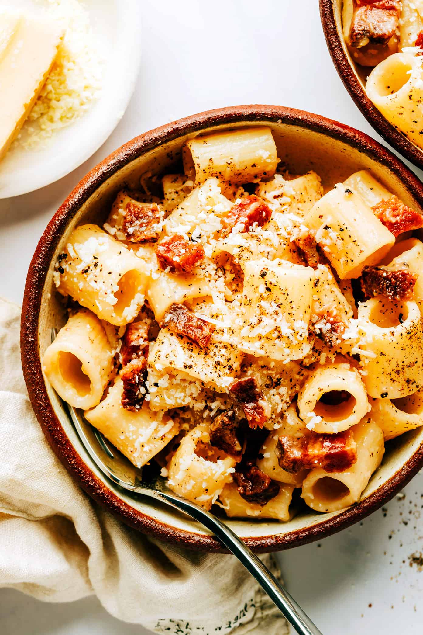 This classic Roman pasta alla gricia recipe is easy to make with 3 ingredients -- bacon (guanciale), cheese (Pecorino) and pasta (rigatoni or spaghetti) and always tastes SO decadent and flavorful. The perfect easy dinner for Italian night! | gimmesomeoven.com Two serving bowls of pasta alla gricia