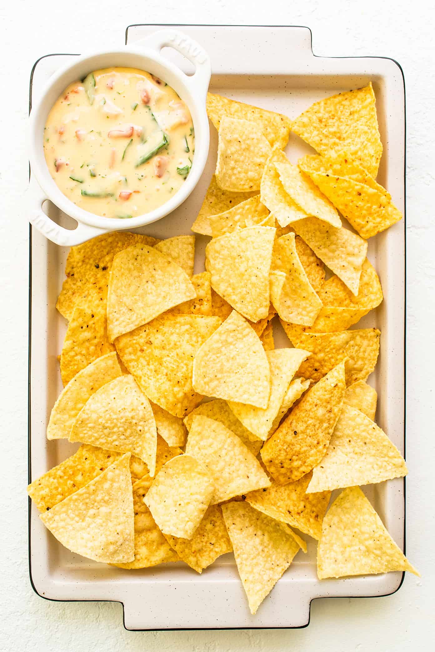 This queso blanco (white cheese dip) recipe is easy to make in about 20 minutes, perfectly melty and scoop-able, and irresistibly delicious. Easy to make with spinach, tomatoes, chiles and the perfect blend of melting cheeses in just 15 minutes, and always everyone's favorite appetizer! | gimmesomeoven.com Chips and Queso Blanco on Sheet Pan