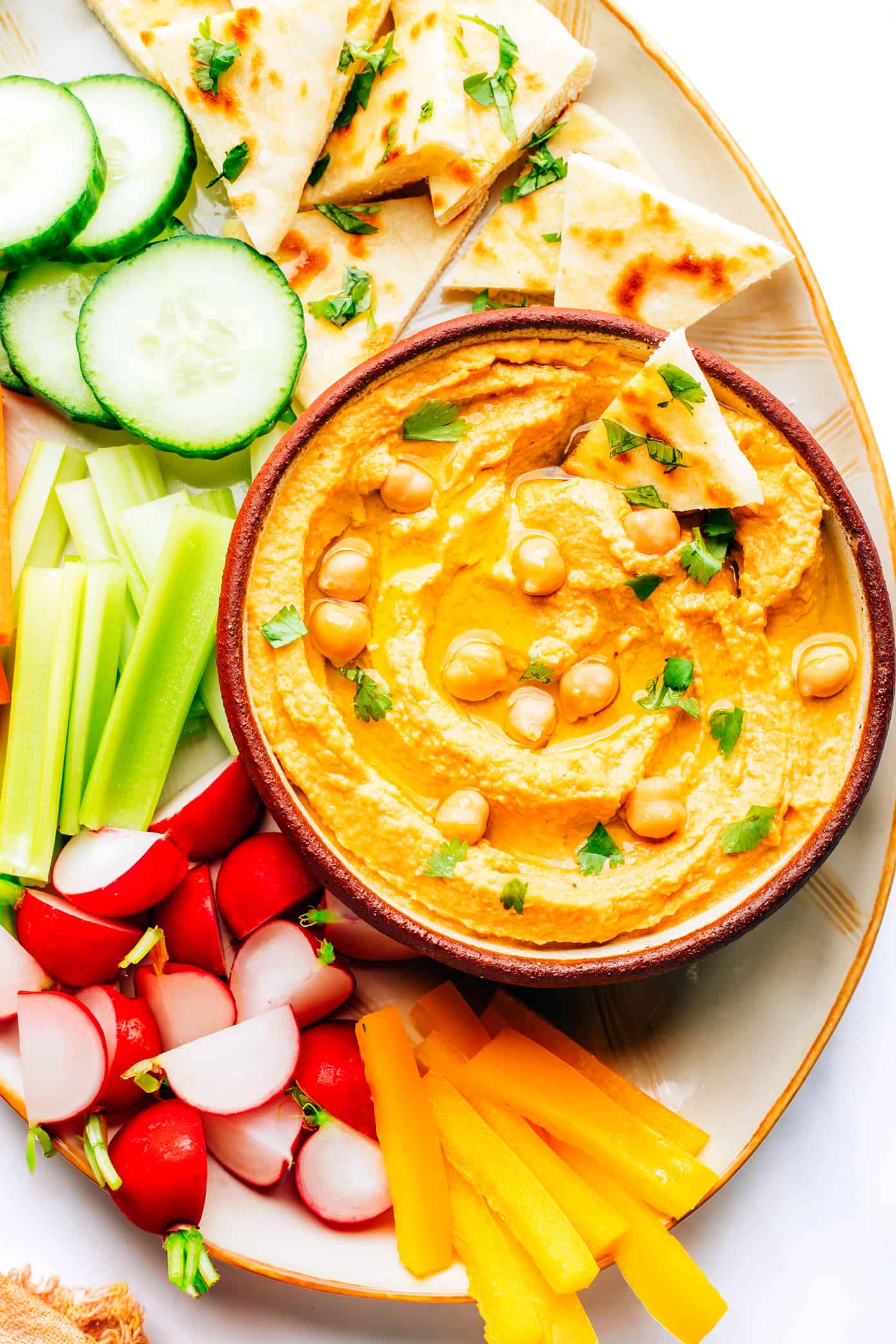 This Thai-inspired red curry hummus recipe is quick and easy to make in just 10 minutes with chickpeas, tahini, coconut milk, curry paste, ginger and garlic. Serve it up as a dip with cruditรฉs and naan, or use it as a spread on burgers or wraps. Such a great easy appetizer! | gimmesomeoven.com Red Curry Hummus