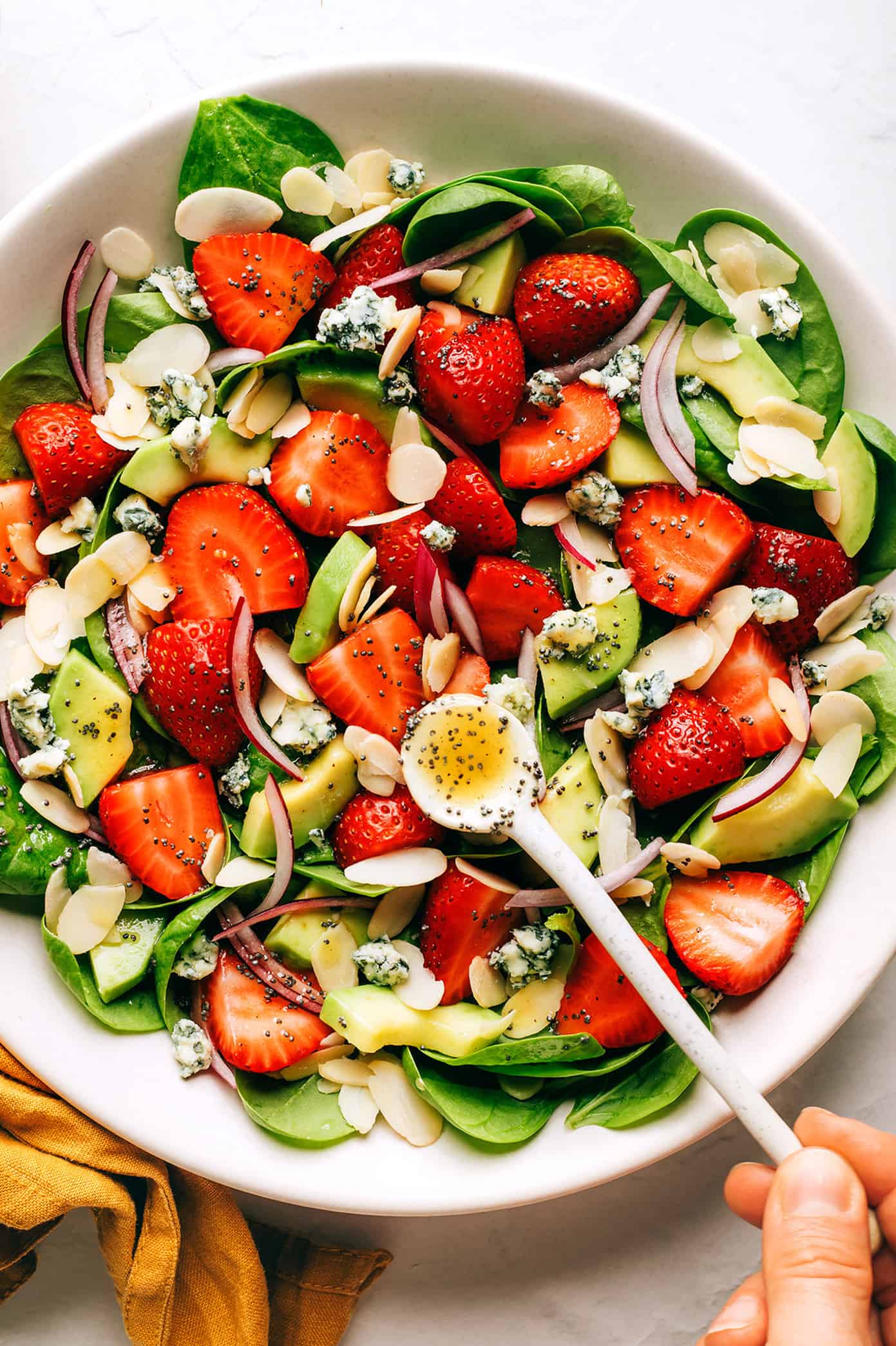 This fresh strawberry spinach salad recipe is tossed with creamy avocado, toasted almonds, sliced red onion, your choice of cheese (blue, feta, goat) and a lightly-sweetened honey poppyseed dressing. Feel free to add in some grilled chicken, shrimp or bacon if you'd like too! | gimmesomeoven.com Strawberry Spinach Salad with Poppyseed Dressing
