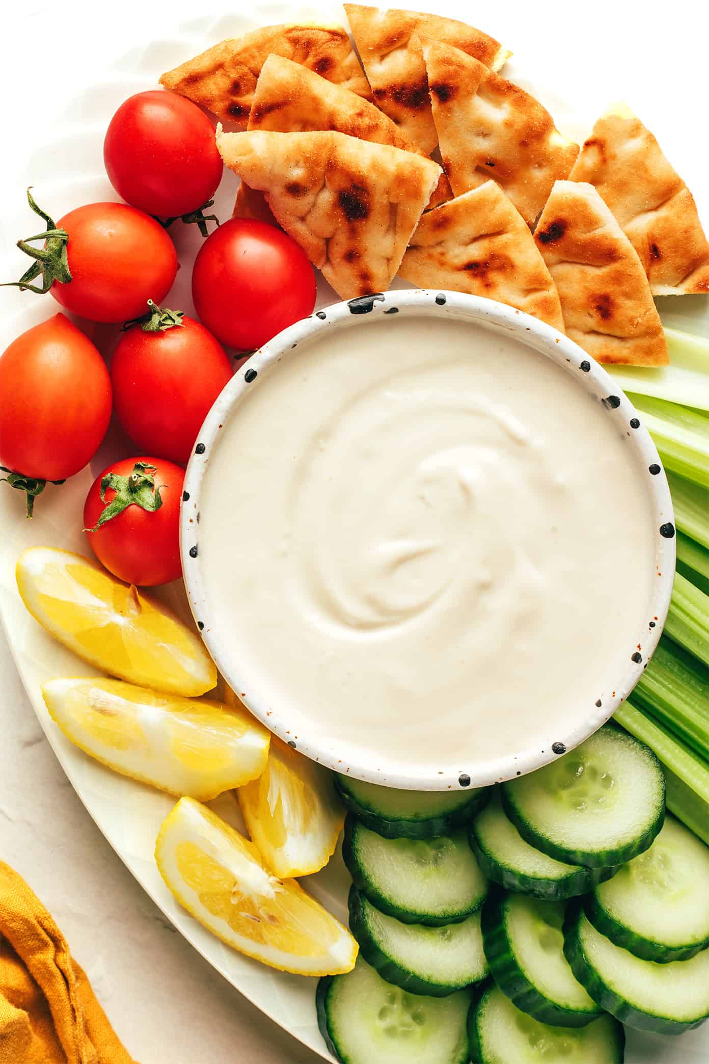 This homemade tahini sauce recipe is quick and easy to make with 5 ingredients and tastes amazing with everything from falafel to roasted veggies, grilled meats, wraps, salads and more. It's naturally gluten free and vegan, and easy to customize with extra herbs, spices or sweetener if you'd like. | gimmesomeoven.com Tahini sauce in bowl with veggies and pita for dipping