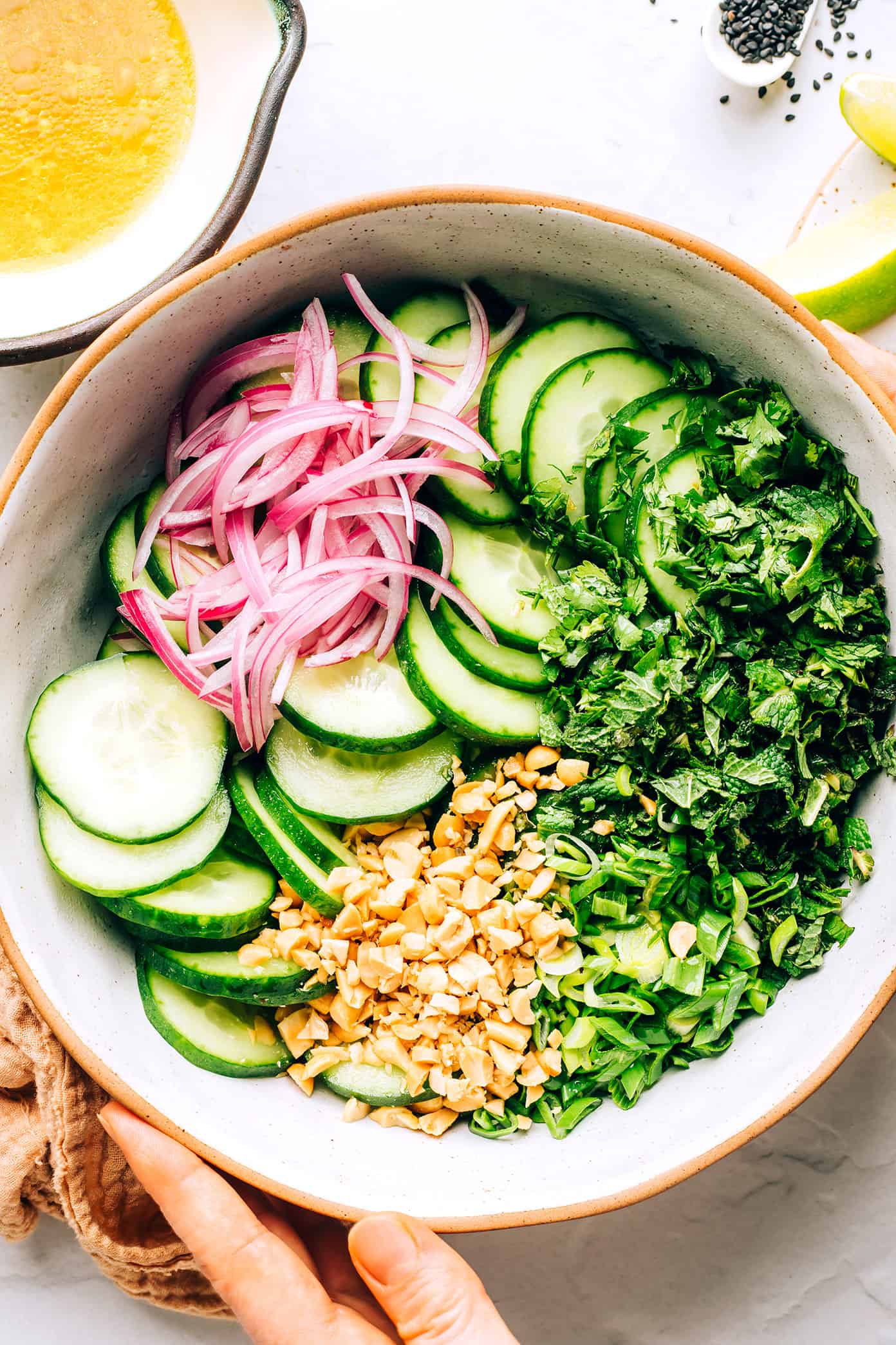 This Thai cucumber salad recipe is loaded up with fresh cucumbers, onions, herbs and peanuts and tossed with a quick zesty lime dressing. It's the perfect cold side dish, and it's naturally gluten-free and can be made vegetarian/vegan too. | gimmesomeoven.com Thai Cucumber Salad Ingredients in Mixing Bowl
