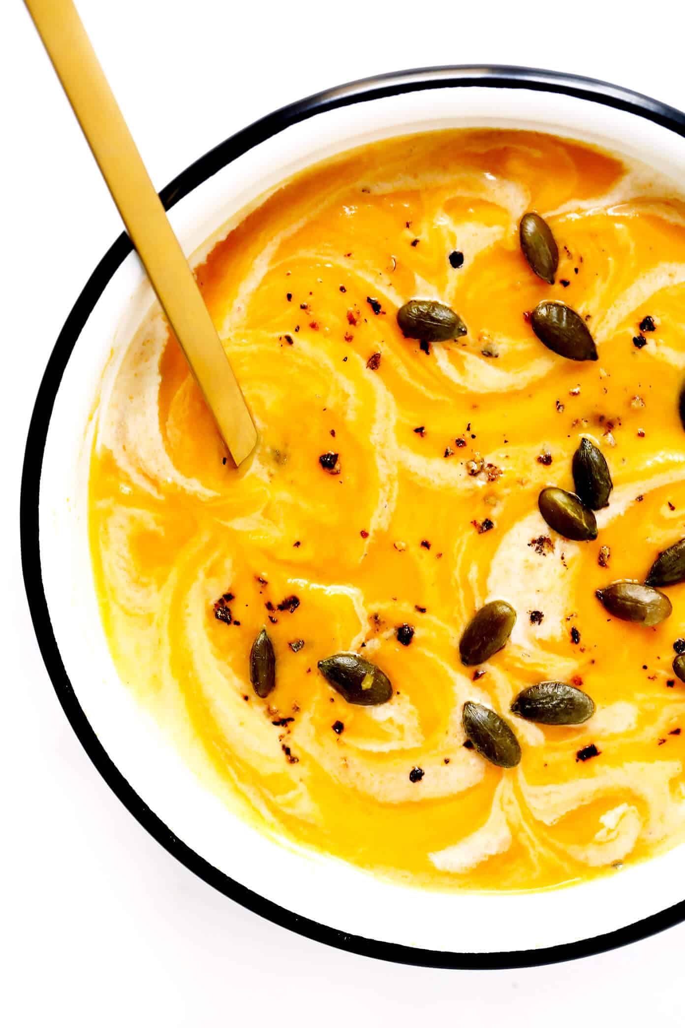 This delicious Butternut Squash Soup recipe is quick and easy to make, loaded up with savory fall vegetables, lightened up with coconut milk (no heavy cream needed), and SO cozy and delicious. Naturally gluten-free, vegetarian, vegan and easy to make in either the Instant Pot, Crock Pot, or on the stovetop. The perfect healthy comfort food dinner recipe for fall or winter! | gimmesomeoven.com Vegan Butternut Squash Soup in Bowl with Pepitas